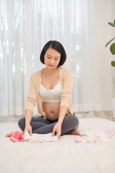 Zwangere Aziatische Vrouw Kijken Kleine Kleren Voor Haar Baby — Stockfoto