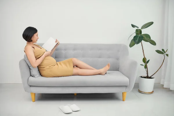 Концепция Беременности Материнства Улыбающаяся Беременная Женщина Лежит Диване Читает Книгу — стоковое фото