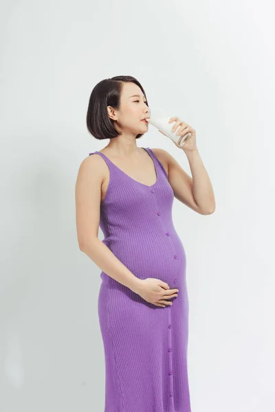 孕妇拿着一杯鲜牛奶 双手放在白色背景下触摸腹部的特写镜头 — 图库照片
