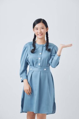 Beyaz arka planda duran genç Asyalı kadın avucunun içinde neşeli bir şekilde sunum yapıyor.