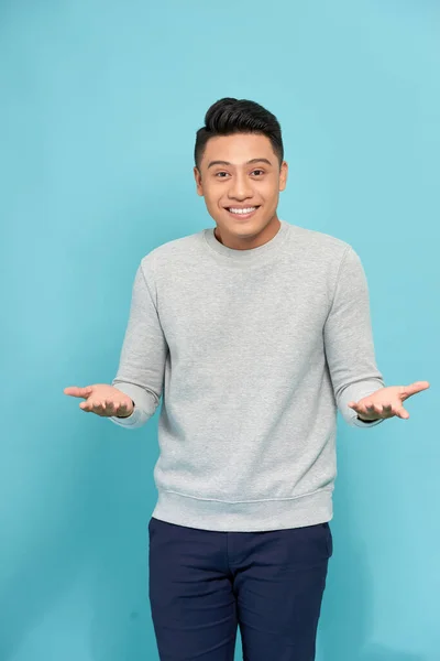 Young happy handsome Asian man raising his hands with open palms gesture