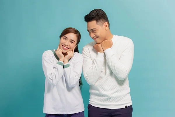 Surprised emotional millennial couple gesturing over blue studio background