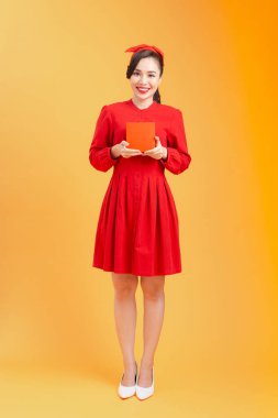 Kırmızı hediye kutusu olan Asyalı genç bir kadının vücut portresi. Turuncu arkaplan izole edildi.