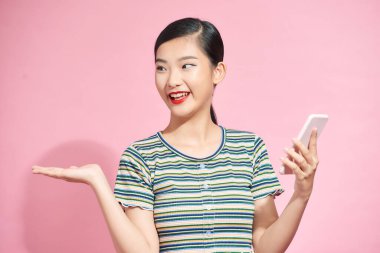 Neşeli kadın akıllı telefonun kamerasına el sallıyor, pembe arka planda video görüşmesi yapıyor. Merhaba, dostum.