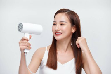 Saçını saç kurutma makinesiyle kurutan güzel kız.