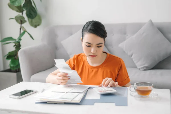 sad woman at living room couch calculating monthly expenses