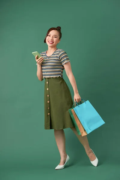 一个拿着购物袋和手机的快乐年轻女子的全长肖像 — 图库照片