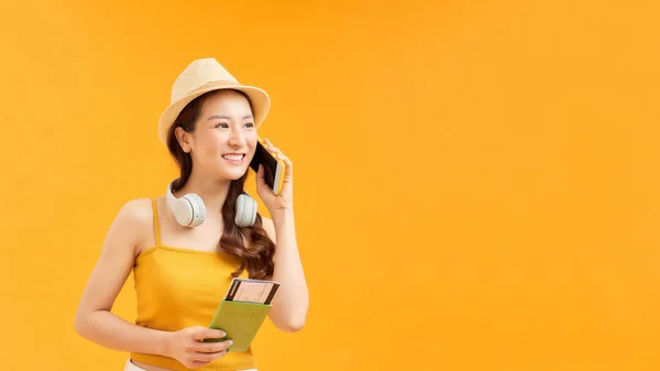 一个快乐的女人在黄色背景下拿着手机和护照的画像 — 图库照片