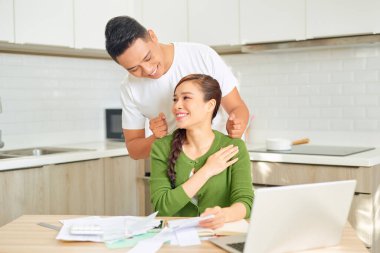 Adam kız arkadaşına masaj yapıyor, o da dizüstü bilgisayarla çalışıyor.