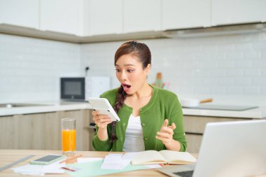 Genç bayan mutfaktaki evinin faturalarını kontrol ediyor.