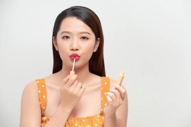 Çekici ve güzel Asyalı kız dudaklarını bej rengi ruj ile boyuyor.