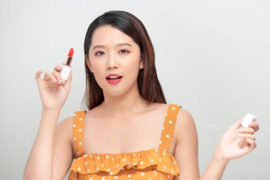 Gözlüklü güzel bir kadın ruj sürüyor, beyaz tenli.