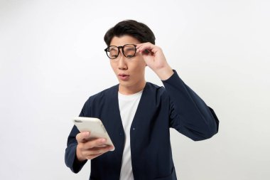 Cep telefonuna bakan mutlu Asyalı adam beyaz arka planda iyi haberler okudu..