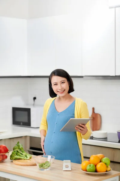 Usmívající Mladá Těhotná Žena Pomocí Digitální Tablet Při Vaření Kuchyni — Stock fotografie