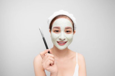 Genç Asyalı kadın yüzüne kilden maske takıyor. Güzellik, cilt bakımı.