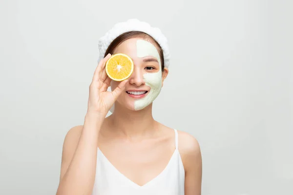 Mooie Vrouw Krijgt Gezicht Klei Masker Het Houden Van Oranje — Stockfoto