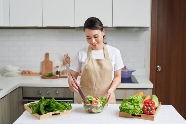 Genç aşçı rahat mutfakta salata hazırlıyor.