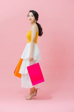 Pembe arka planda tek başına duran günlük kıyafetler giyen güzel bir genç kız.