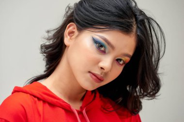 Ciltli, kıvırcık saçlı, parlak makyajlı güzel bir kadın.