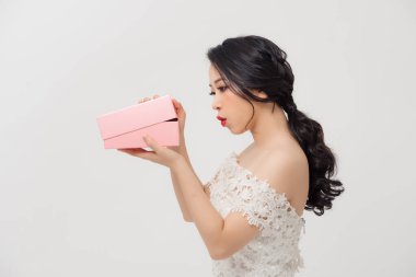 Genç zarif Asyalı kadın beyaz arka planda izole edilmiş hediye kutusunu açıyor..