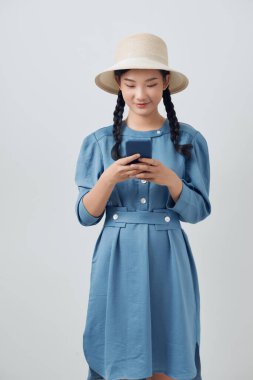 Cep telefonu kullanırken gülümseyen Asyalı genç kadının stüdyo fotoğrafı.