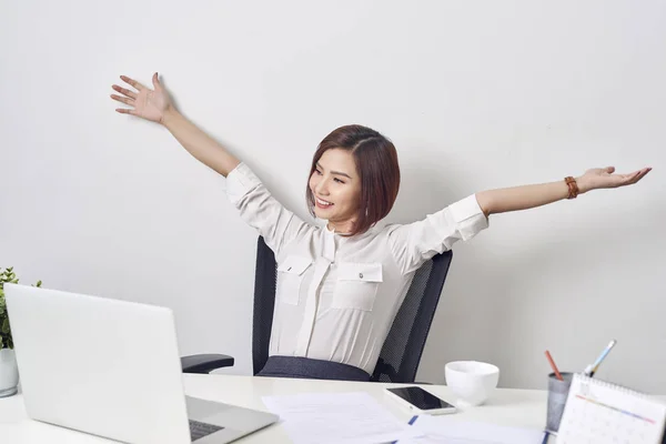 Satisfied woman relaxing with hands behind her head. Happy smiling employee  after finish work, reading good news, break at work, girl doing simple  exercise, relieve muscle stress, feeling well — sitting, Vietnamese -