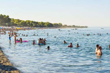 Paralia Skotinas, Yunanistan - 29 Temmuz 2017: Tatilcilerin bir yaz güneşli akşam sahilde.