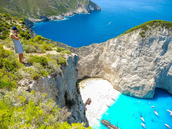 Tourist near the clifff edge on the Shipwreck Bay background, Zakynthos Island, Greece.