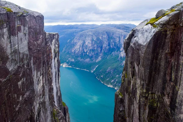 View of Lysefjorden through a crevice between two cliffs 984 meters high, where the famous Kjeragbolten stuck nearby - the most dangerous stone in the world. Mountain Kjerag, Rogaland county, Norway.