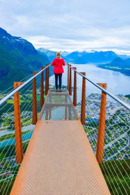 Rampestreken yürüyüşü. Rampestreken Viewpoin 'deki turist kız. Panoramik manzara Andalsnes şehri Romsdal Fjord kıyılarında, pitoresk dağlar arasında yer alır. Ve tuzaklar. Norveç