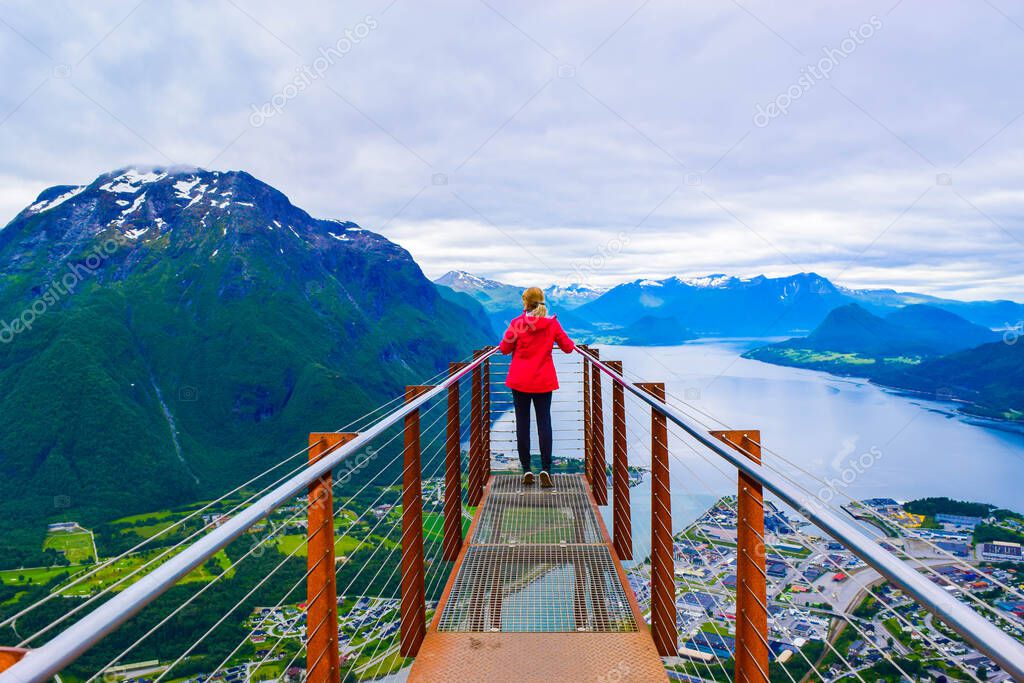 Hiking Rampestreken. Tourist girl on the Rampestreken Viewpoin. Panoramic landscape Andalsnes city located on shores of Romsdal Fjord between the picturesque mountains. Andalsnes. Norway