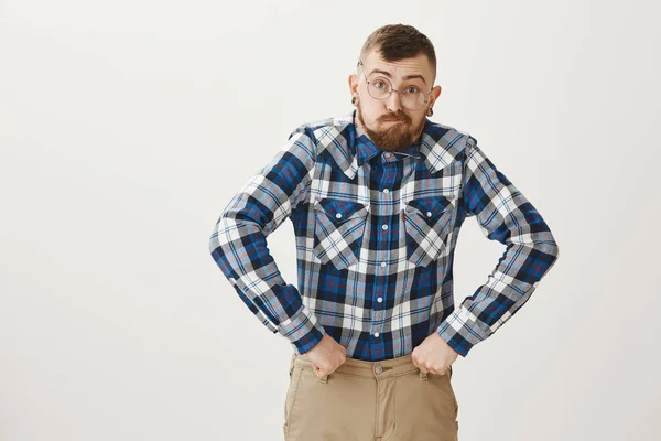 Guy got old too quickly. Funny talented male actor in glasses and blue plaid shirt mimicking grandfather, making faces and holding clenched fists near hips in hilarious pose, standing over gray wall