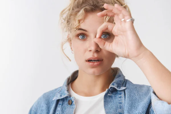 Close-up wondered attractive sensual feminine blond european blue-eyed woman curly haircut open mouth surprised make okay ok gesture look through circle amazed, standing amused white background
