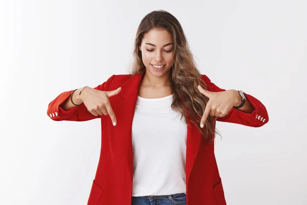 Curious good-looking young modern businesswoman wearing red trendy jacket pointing looking interested up smiling amused delighted finding good copy space, great promotion, white background