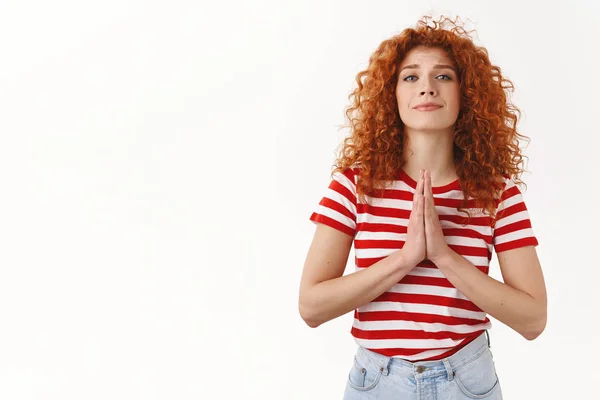 Please I need you. Attractive tender feminine curly redhead woman asking favour press palms pray gesture plead smiling gently wanna receive help begging coworker cover, standing white background