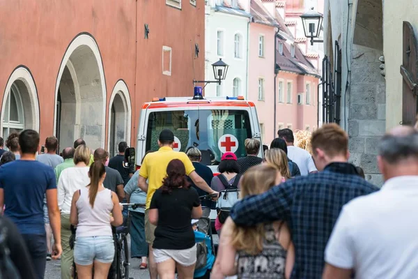 Ambulance with blue lights and a crowd of people, Regensburg - Germany