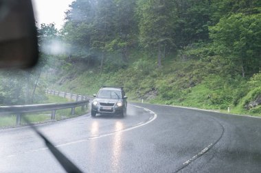 Yağmurlu yol yüzeyi ve bir araba ön cam üzerinde yağmur damlaları