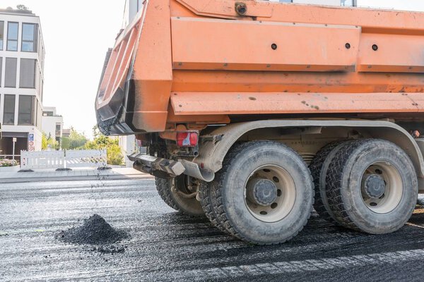 A dump truck brings hot asphalt for the renewal of a road pavement, Germany