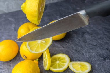 Keskin bir mutfak bıçağı dilimler halinde düşen limon keser