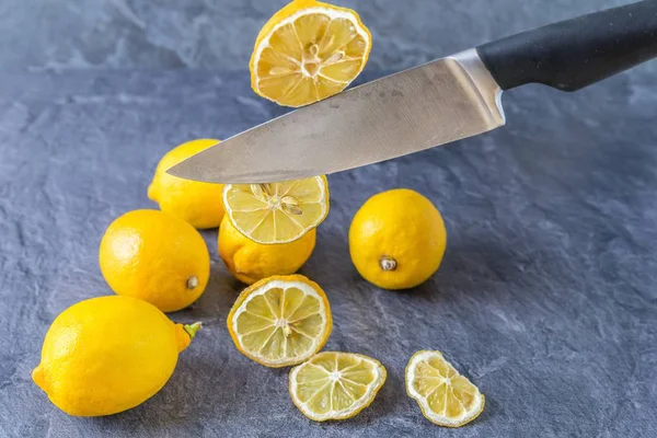 Keskin bir mutfak bıçağı havada dilimler halinde eski bir sedilmiş limon keser