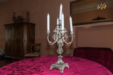 Kadife masa örtüsü ile yuvarlak bir masa üzerinde beyaz mumlar ile gümüşten yapılmış eski antika şamdan