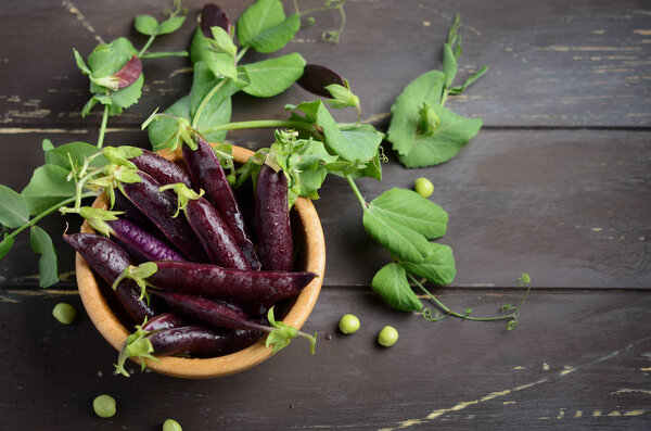 Органический фиолетовый зеленый горошек в деревянной миске на ржавом деревянном столе
.