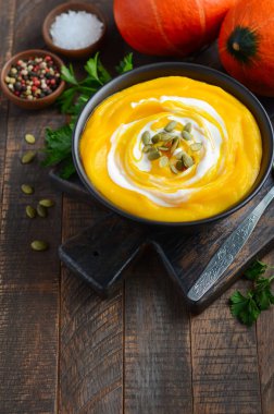Rustik ahşap masa üzerinde krem ve kabak çekirdeği ile kabak kremalı çorba.