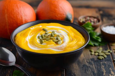 Rustik ahşap masa üzerinde krem ve kabak çekirdeği ile kabak kremalı çorba.
