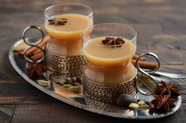 Hint masala chai çay. Rustik ahşap masa üzerinde vintage bir bardak süt ile baharatlı çay.