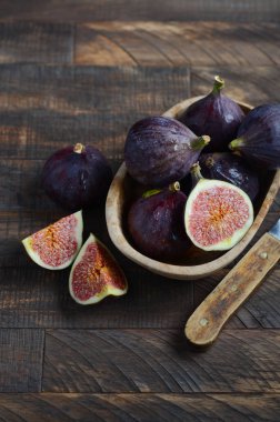 Eski bir ahşap zemin üzerine ahşap bir kase taze incir.