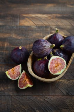 Eski bir ahşap zemin üzerine ahşap bir kase taze incir.