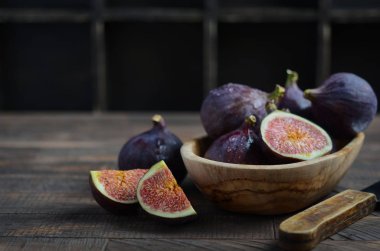 Eski bir ahşap zemin üzerine ahşap bir kase taze incir.