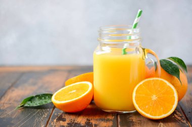 Seçici odak eski ahşap masada bir kavanoza taze portakal suyu.