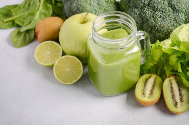Taze yeşil smoothie malzemeler gri beton zemin, seçici odak bir kavanoza.